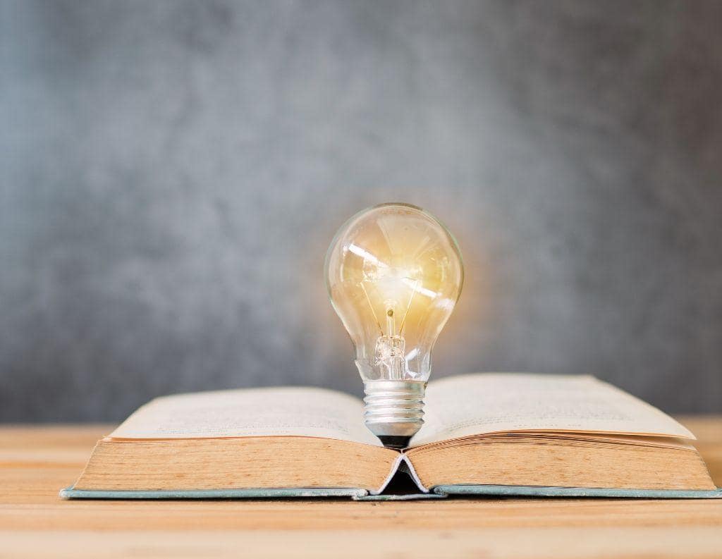 Aufgeschlagenes Buch mit leuchtender Glühbirne, symbolisiert klare Lösungen für berufliche Herausforderungen, Zufriedenheit und Work-Life-Balance.